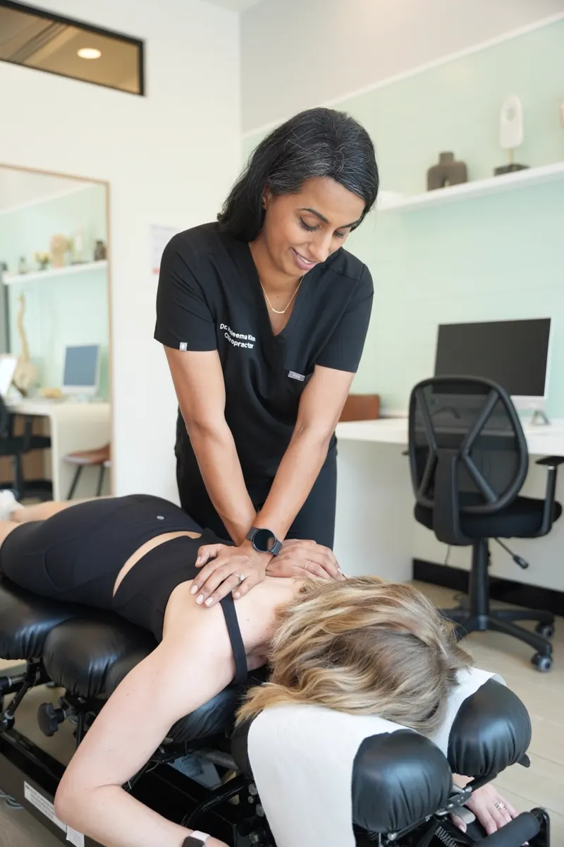 Dr. Haleema Khan giving a gentle upper back adjustment on a treatment table