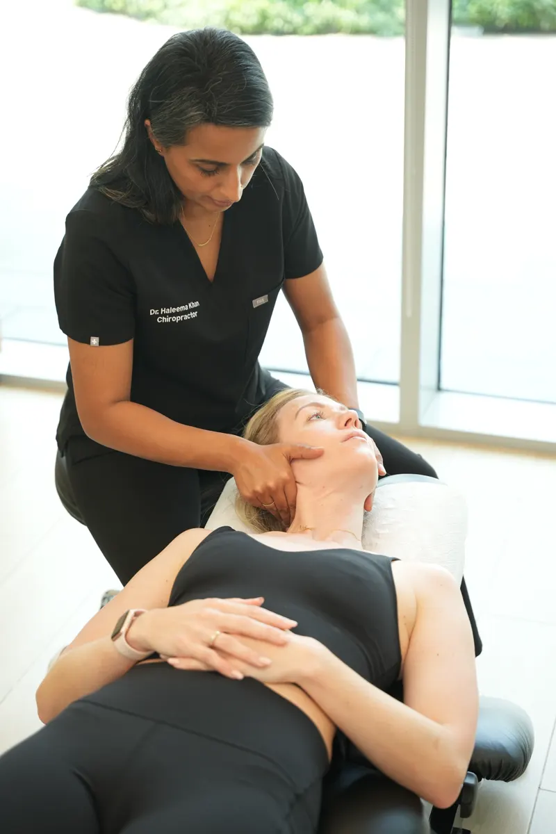 Dr. Haleema Khan giving a gentle neck adjustment to a patient lying on her back